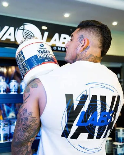 A customer at the Titan Lab counter holding YAVA Labs Vegan Protein in front of the shelf